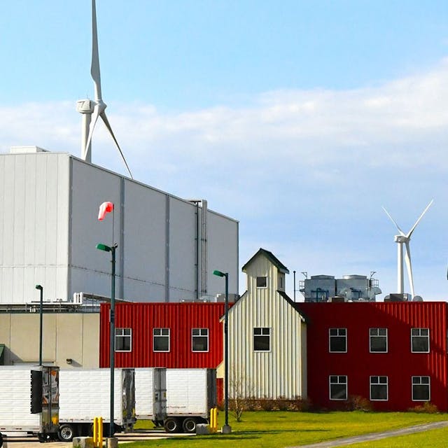 Red storage building with parked semi's and wind turbines.